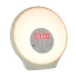 Lumie Sunrise Alarm, en rund väckningslampa i ljust grågrönt med röd digital klocka på 07:00, fotad mot vit bakgrund