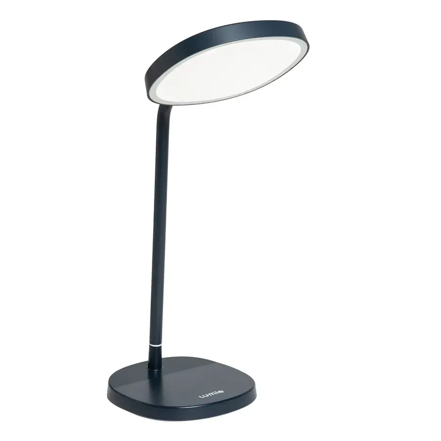Lumie Task i mörkgrå/blå, en skrivbordslampa med böjd arm och rund lampskärm, fotad mot vit bakgrund